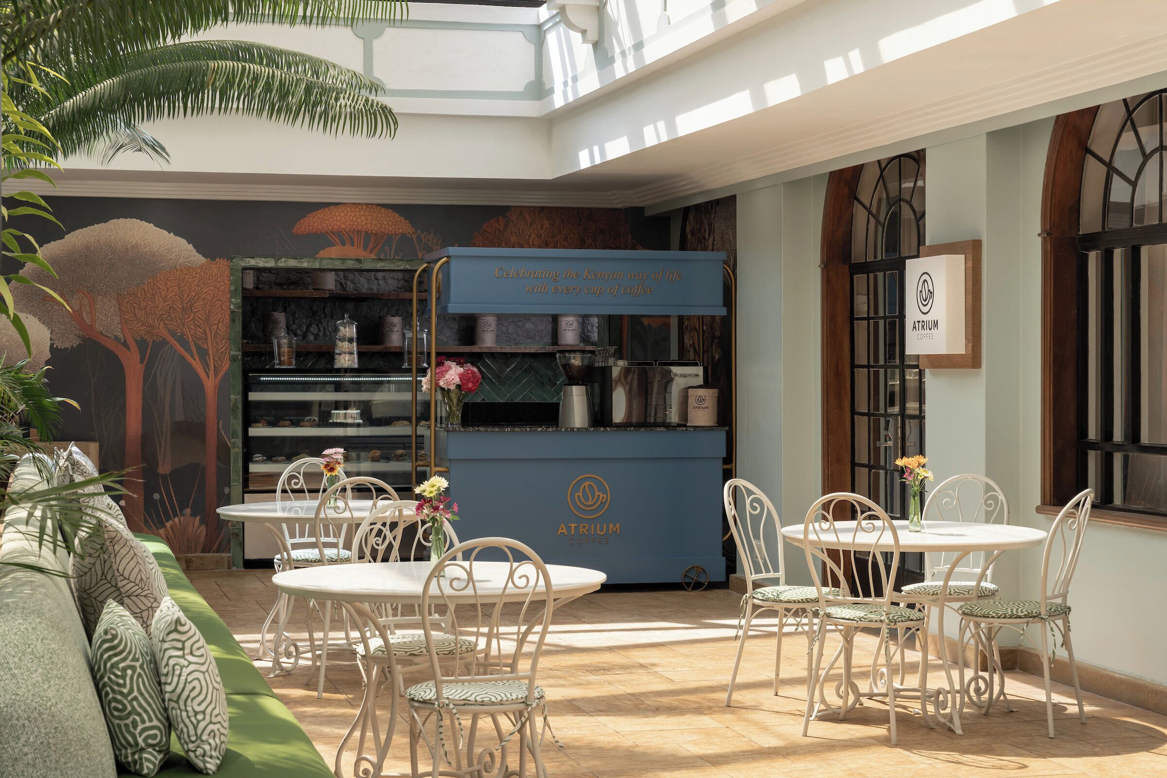 Ein gemütlicher Innenbereich mit Sitzgelegenheiten, einer Kaffeestation, einem Bücherregal und einem Schild mit der Aufschrift 'Atrium Coffee'.