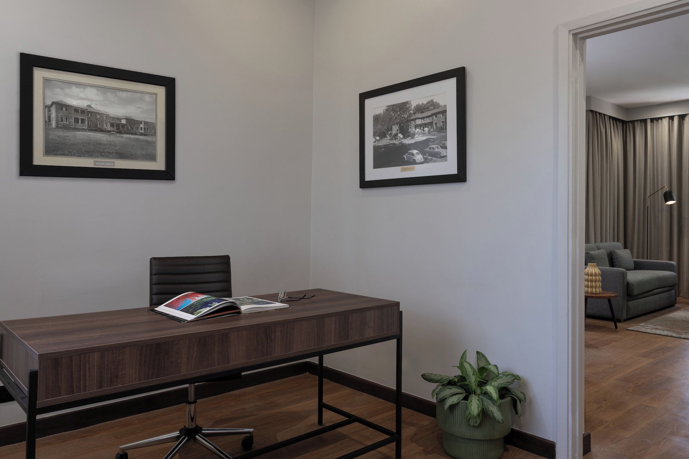 A conference room with a wooden table, two chairs, and framed black and white photographs on the wall.