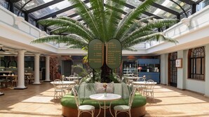 A spacious atrium with a central seating area, a palm tree, and directional signs for rooms and meeting rooms. - Fairview Hotel Nairobi, Vignette Collection by IHG (Nairobi)