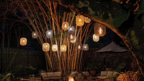 An outdoor seating area with wicker furniture, a central fire pit, and hanging lanterns. - Fairview Hotel Nairobi, Vignette Collection by IHG (Nairobi)