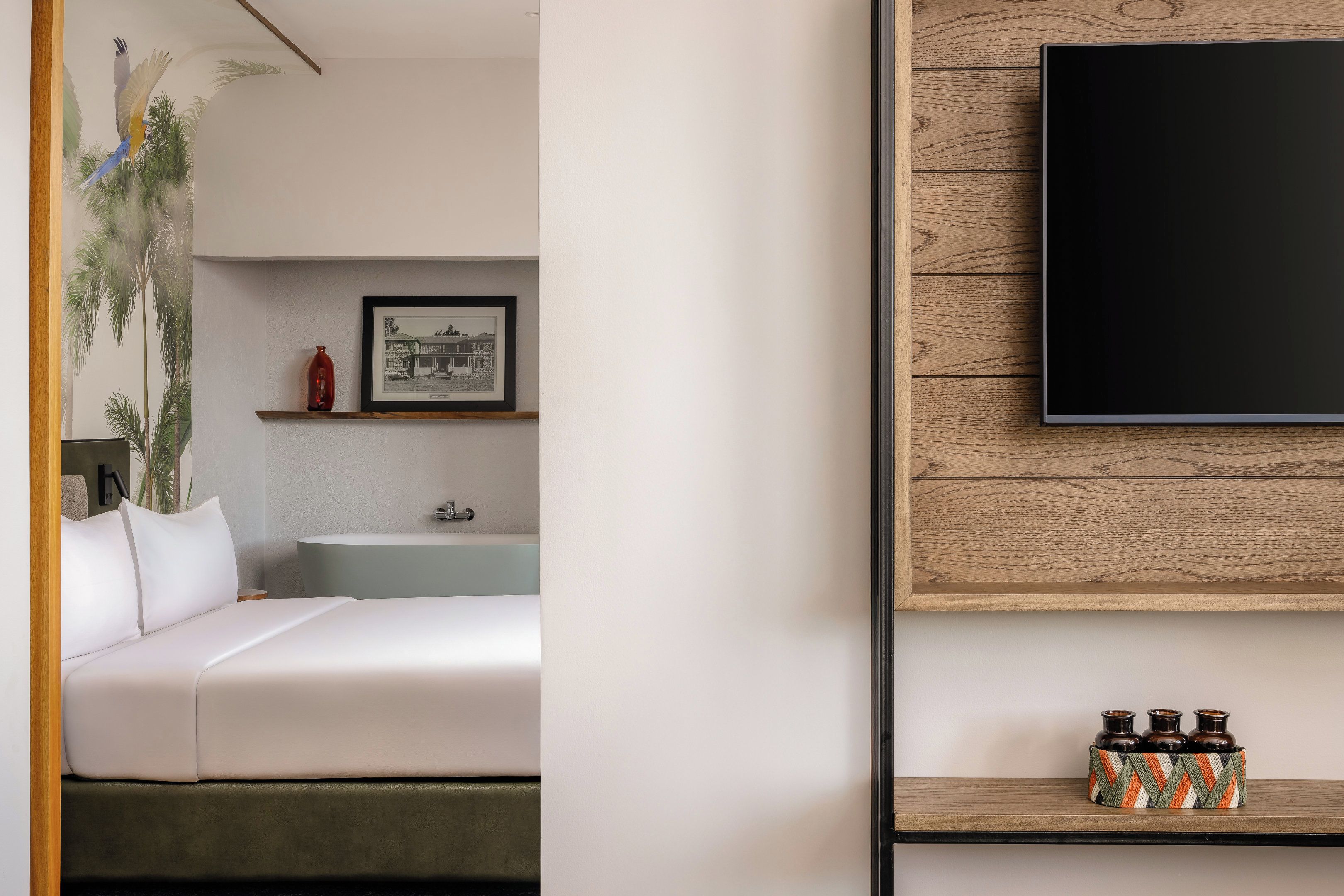 A modern bedroom with a bed, a bedside table, a mounted TV, and a shelf with decorative items.