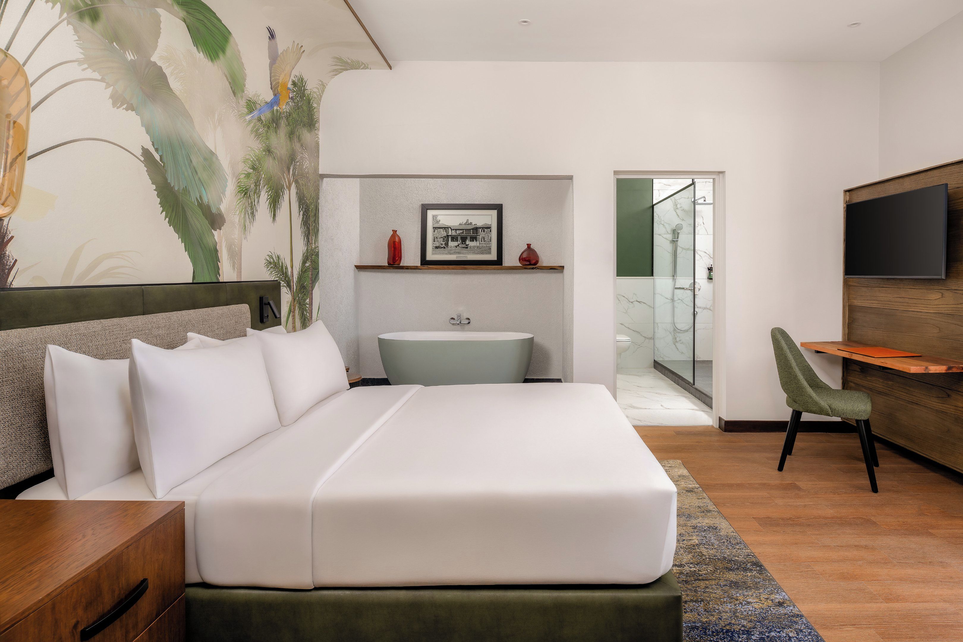 Une chambre moderne avec un grand lit, une petite salle de bain, un bureau et un téléviseur.