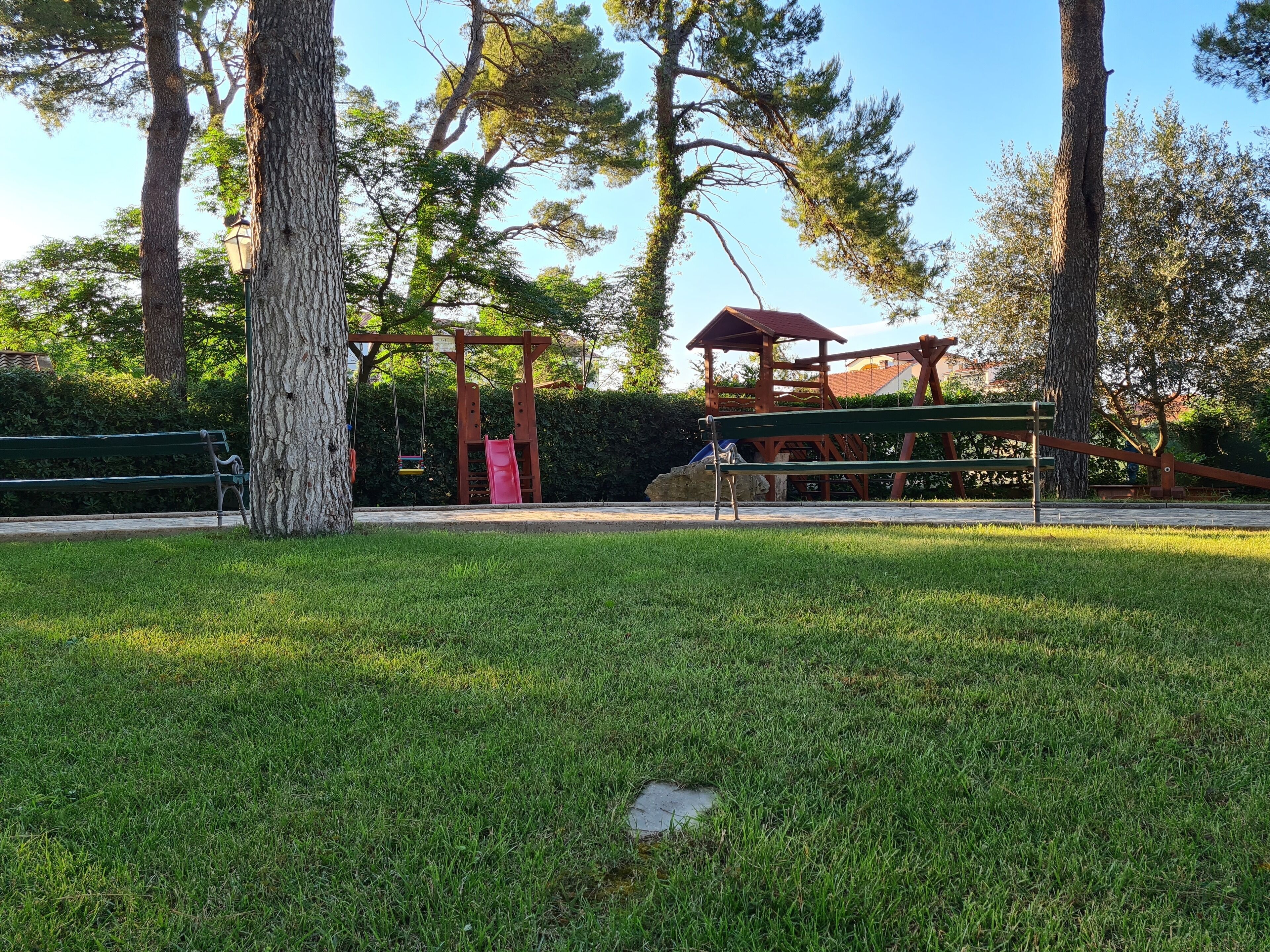 A park with a playground, a bench, and a gazebo.