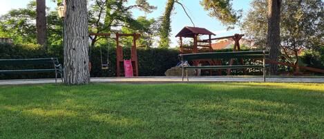 A park with a playground, a bench, and a gazebo.
