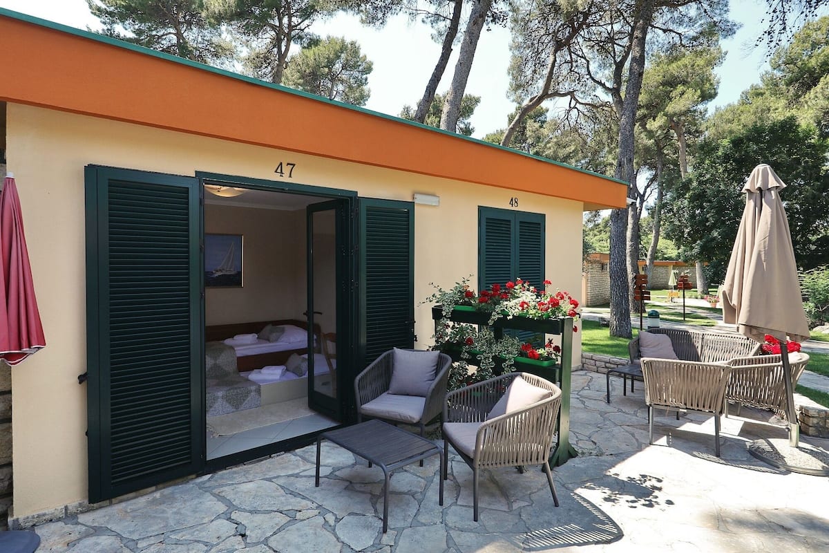 Un espace extérieur accueillant, aménagé avec des meubles en osier et agrémenté d’un arrangement floral.