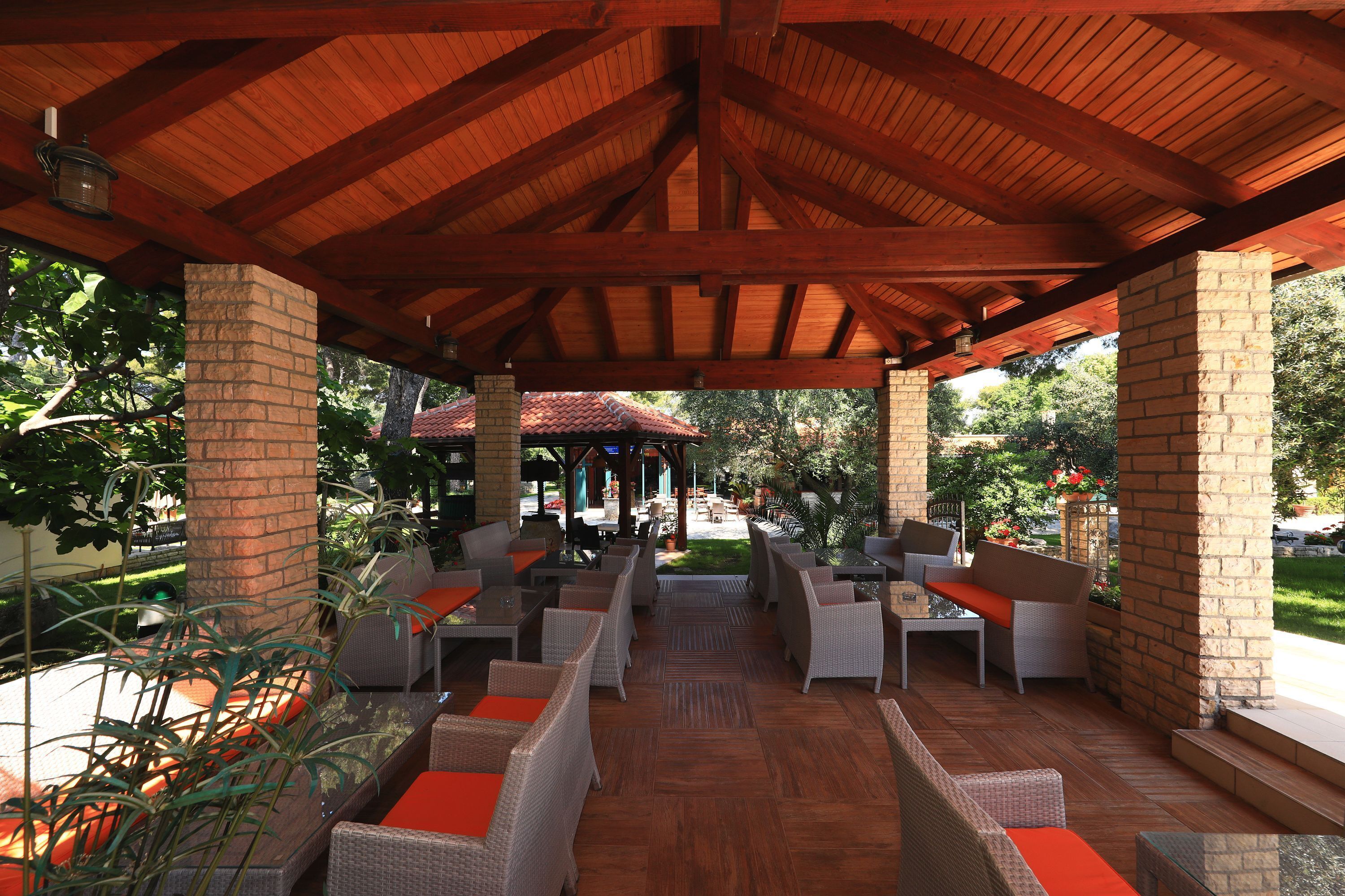 An outdoor patio with wicker furniture and brick pillars.