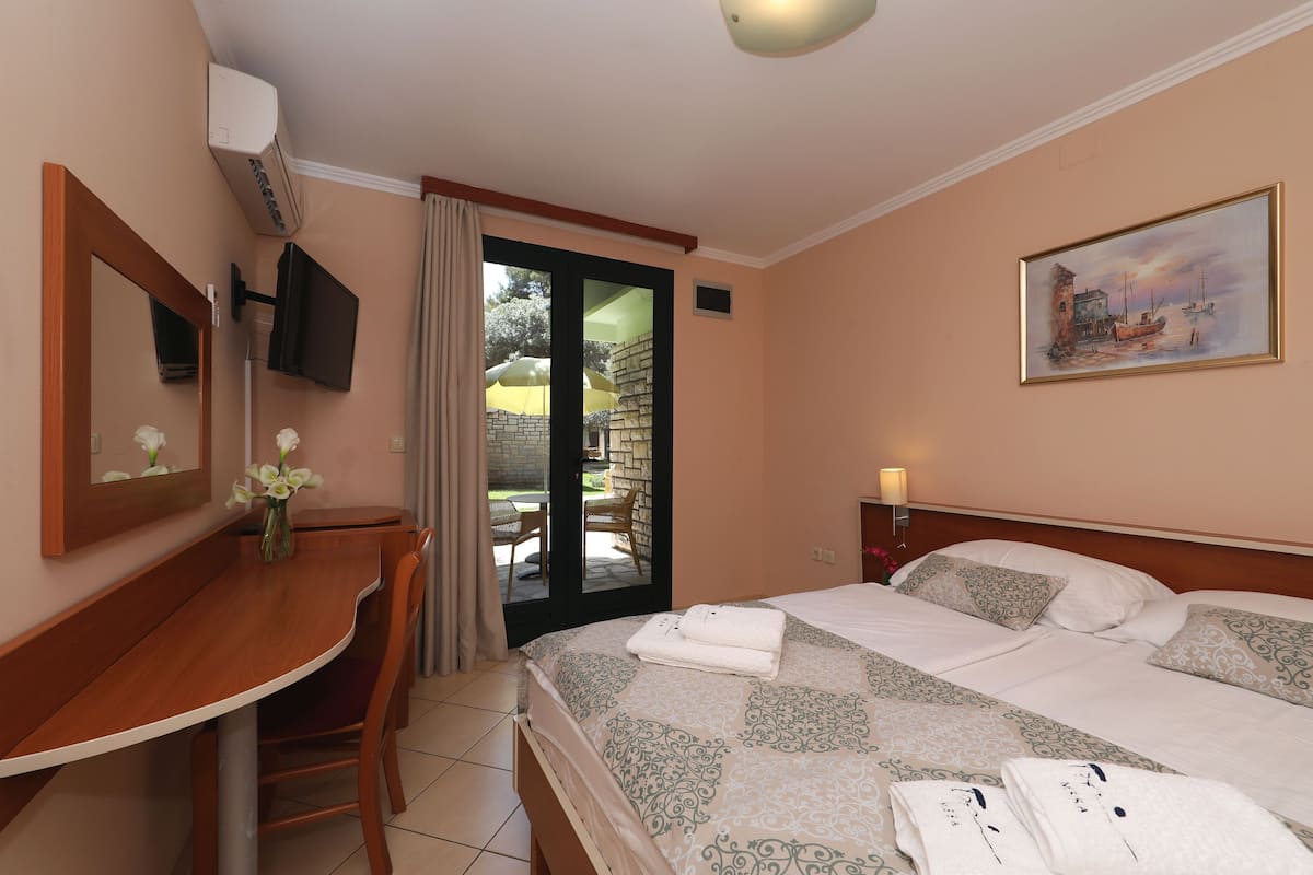 Une chambre d’hôtel avec un lit, un bureau, une chaise, une télévision, un tableau et une vue sur l’extérieur.