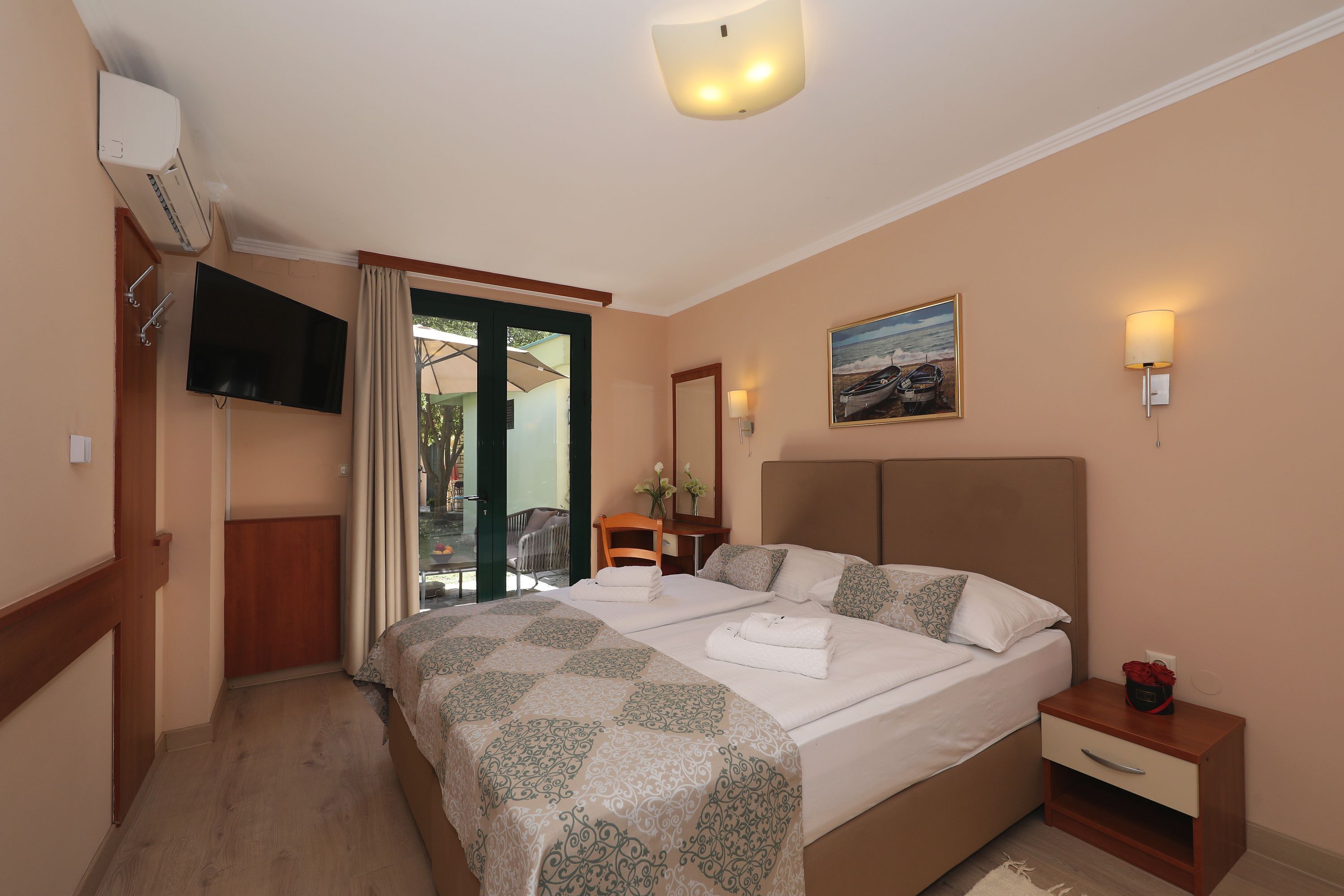 A bedroom with a bed, bedside table, and a TV mounted on the wall.