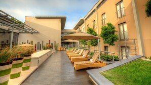 Una terrazza sul tetto con lettini, fioriere e ombrelloni.