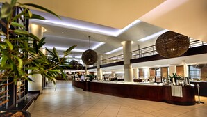 Un'ampia hall con una reception, grandi lampade sferiche a sospensione e una moderna scala.