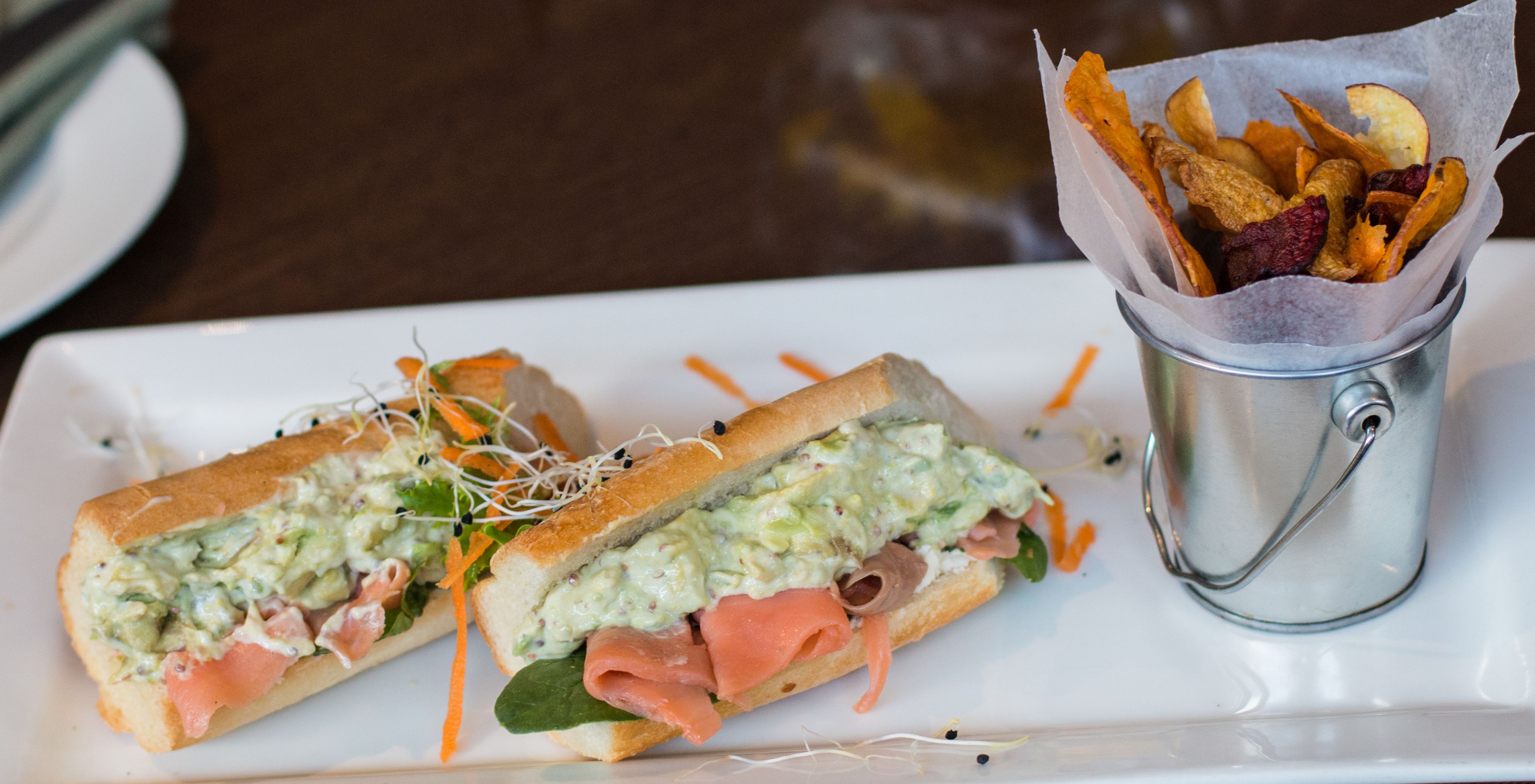 A sandwich with a side of crispy snacks on a white plate.