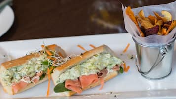A sandwich with a side of crispy snacks on a white plate.