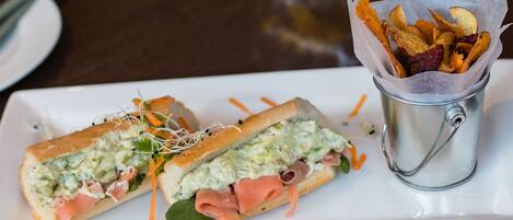 Un sándwich con guarnición de aperitivos crujientes sobre un plato blanco.