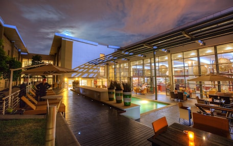 An outdoor pool area with seating and a glass-enclosed restaurant.