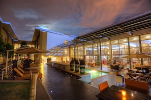 An outdoor pool area with seating and a glass-enclosed restaurant.
