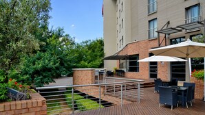 Eine Terrasse im Freien mit Holzboden, Metallgeländer und Gartenmöbeln.