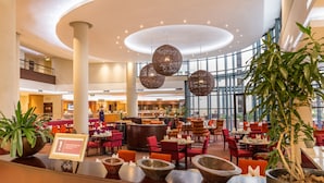 A spacious indoor area with multiple dining tables and chairs, large windows, and hanging spherical light fixtures. - City Lodge Hotel Hatfield (Pretoria)
