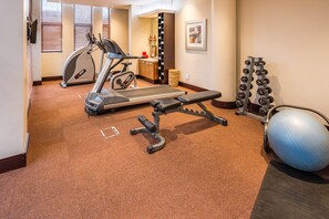 A home gym with exercise equipment including a treadmill, elliptical, bench press, dumbbells, and a medicine ball. - City Lodge Hotel Hatfield (Pretoria)