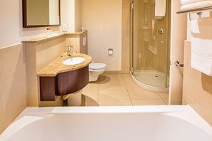 A modern bathroom with a freestanding bathtub, a sink with a granite countertop, a toilet, and a glass-enclosed shower area. - City Lodge Hotel Hatfield (Pretoria)