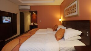 A hotel room with a large bed, a TV on the left, an air conditioner above the bed, and a framed picture on the wall. - City Lodge Hotel Hatfield (Pretoria)