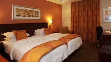 A hotel room with a large bed, a desk, and a chair.