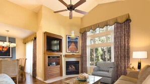 Una sala de estar con chimenea, televisor y ventilador de techo.
