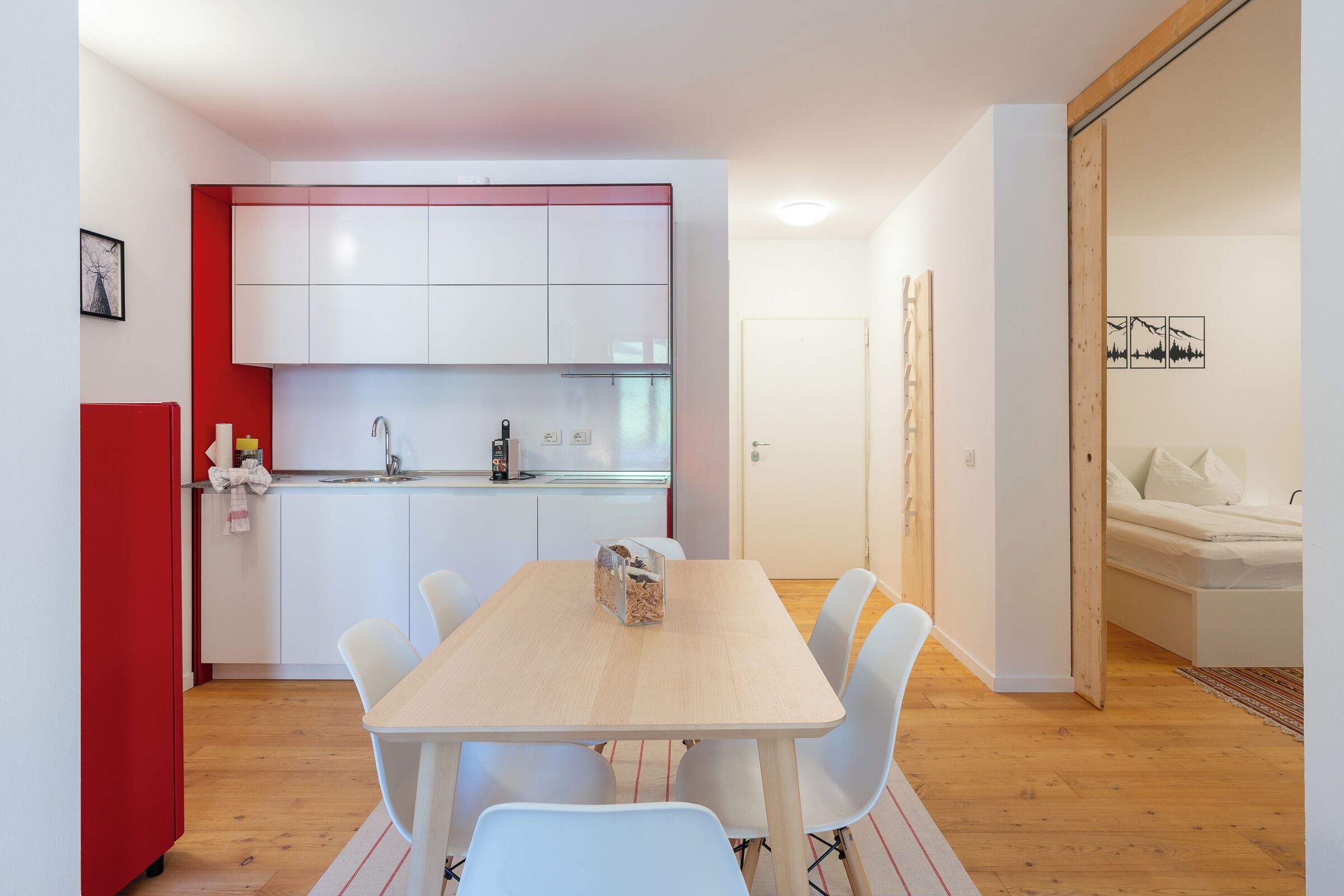 A modern kitchen with white cabinets and a wooden dining table.