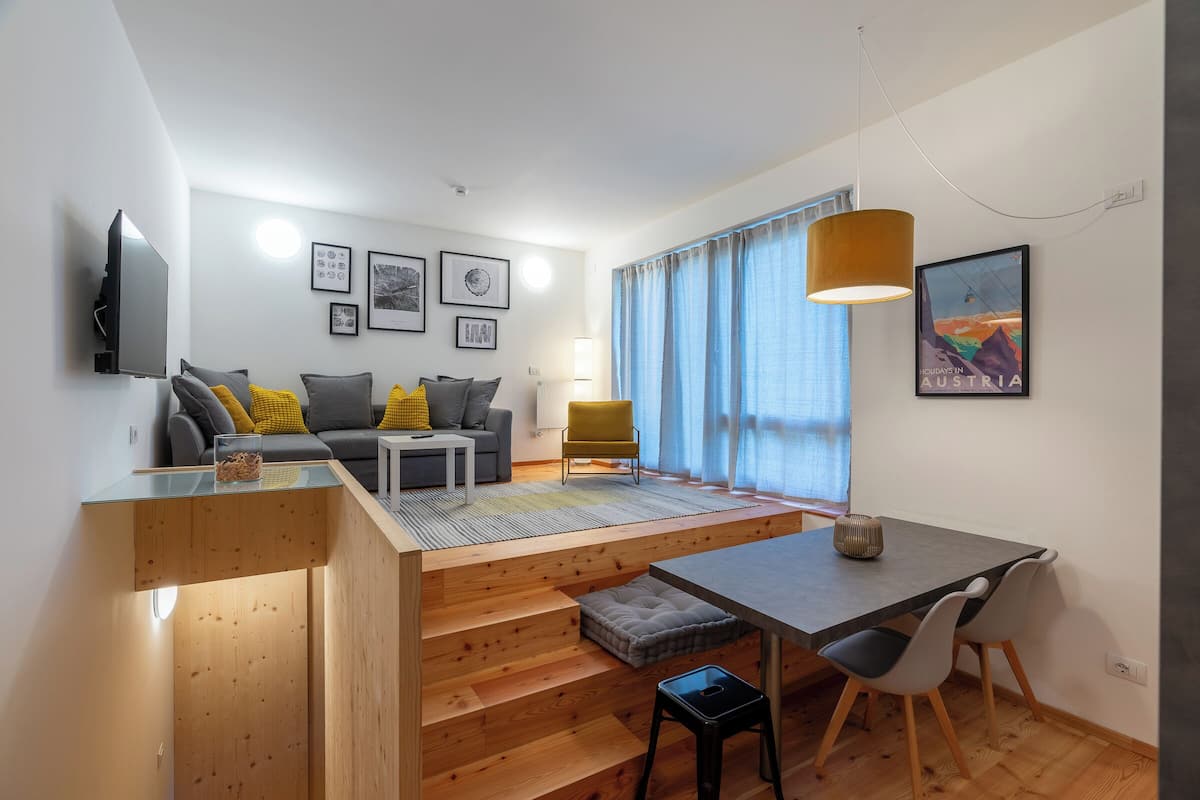 A modern living space with a sofa, coffee table, and a dining area with a table and chairs.