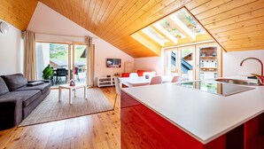 A modern kitchen with a large island, wooden ceiling, and a dining area with a sofa and table. - Quercus Appartements (Reichenau)