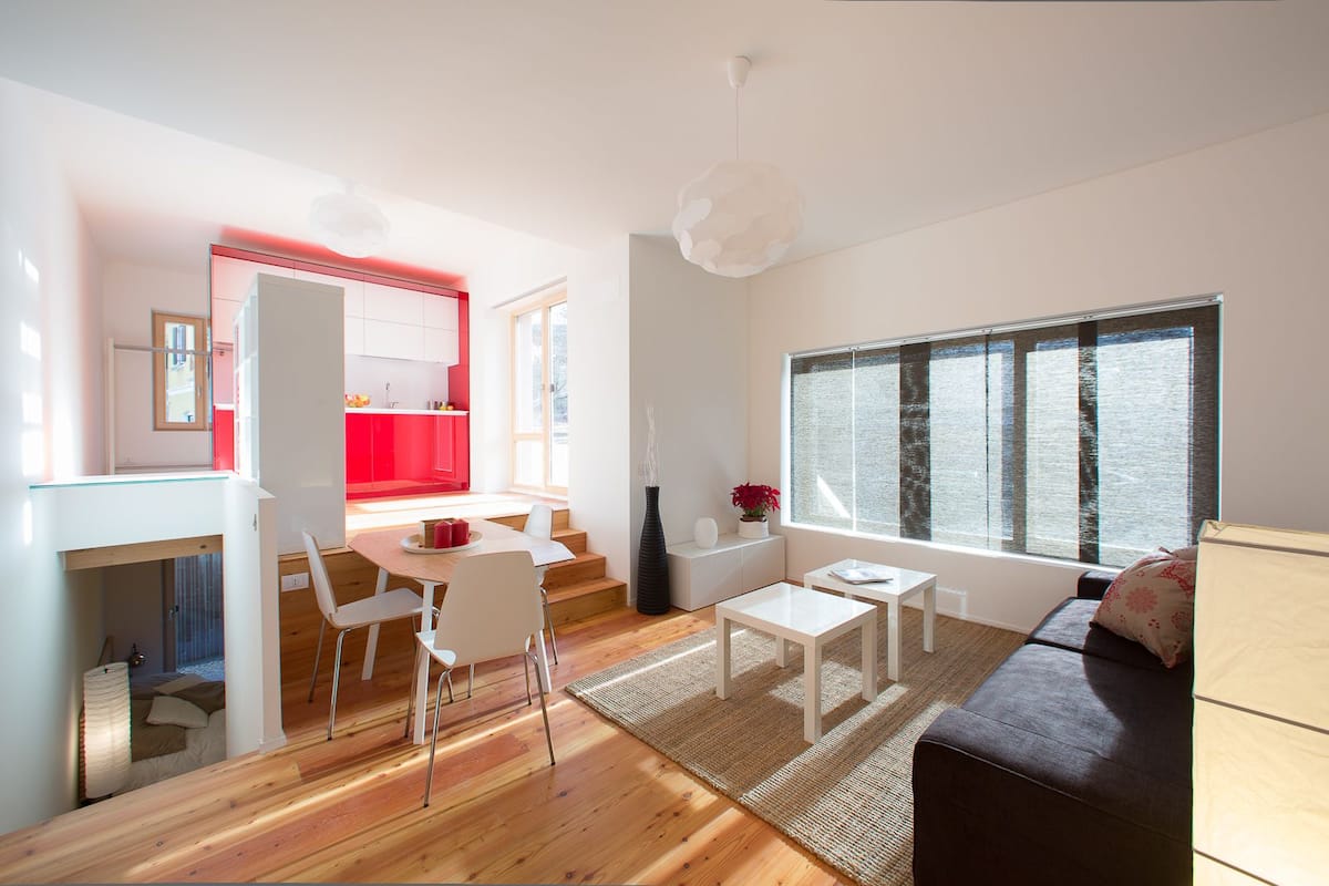 A modern living space with a dining area, a sofa, and a large window.