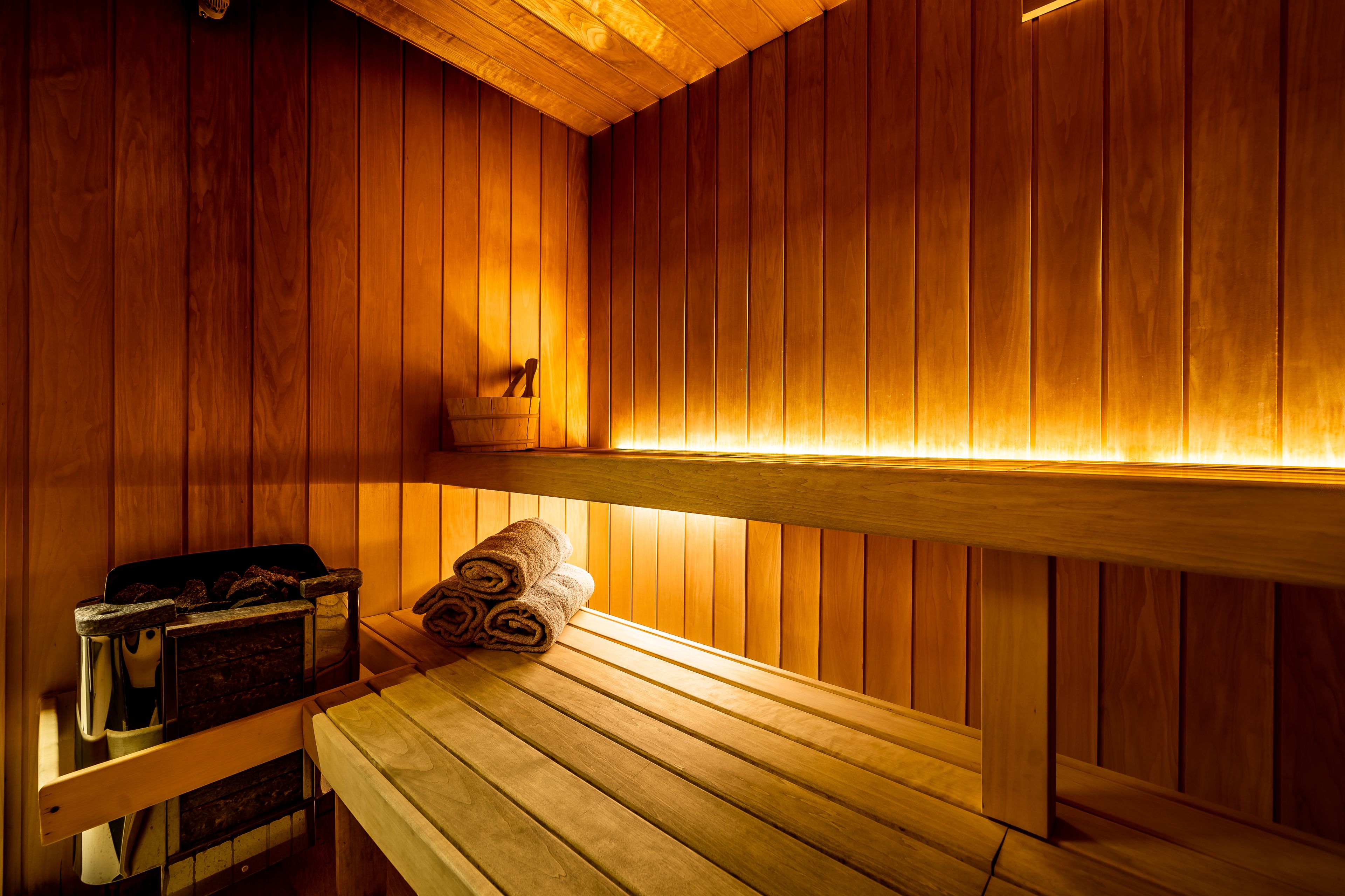 A wooden sauna with benches and a bench with towels.