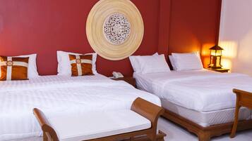 A hotel room with two beds, a decorative wall hanging, a bedside lamp, and a telephone on the nightstand.