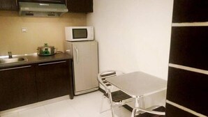 Una cocina compacta equipada con microondas, un refrigerador pequeño y una mesa metálica con sillas.