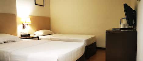 A hotel room with two beds, a desk, a lamp, and a coffee machine.