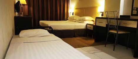 A hotel room with two beds, a desk, a chair, a lamp, and a curtain.