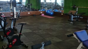 Un gimnasio con equipo de ejercicio, un ventilador de techo y un espejo grande.