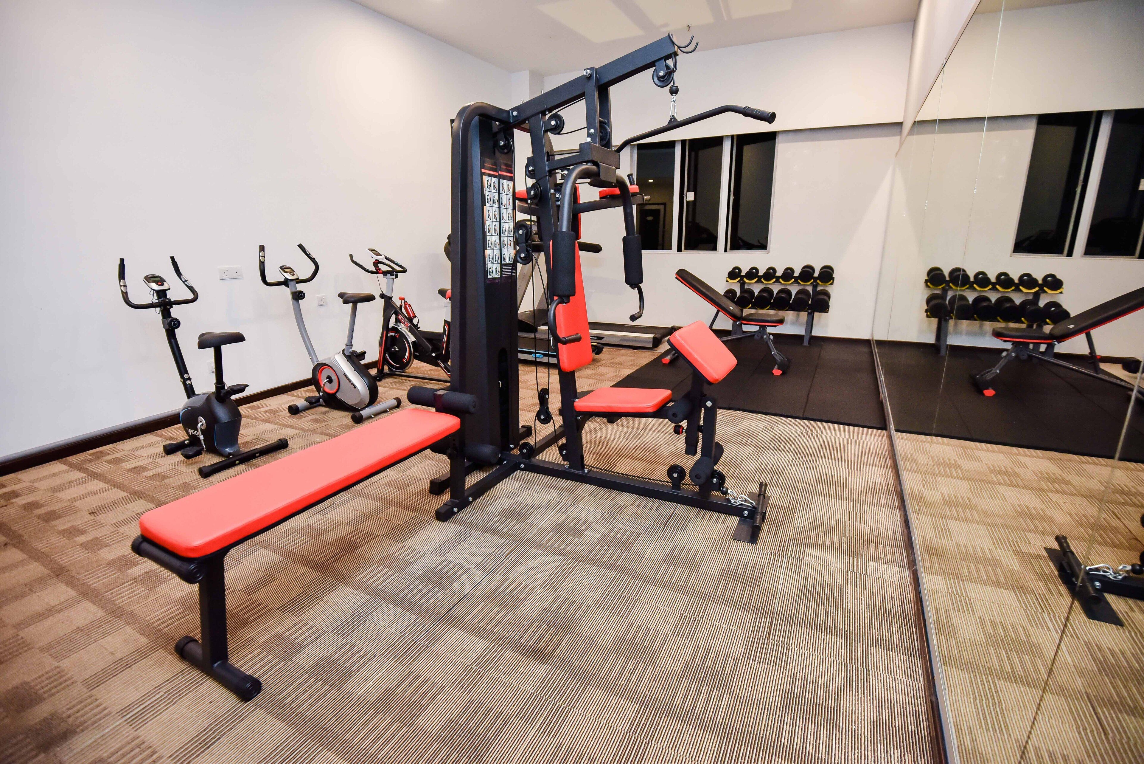 A gym with exercise equipment, benches, and dumbbells.