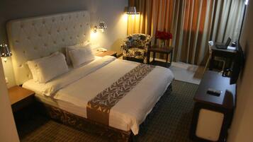 Una habitación de hotel con una cama grande, una silla, un escritorio y una lámpara.