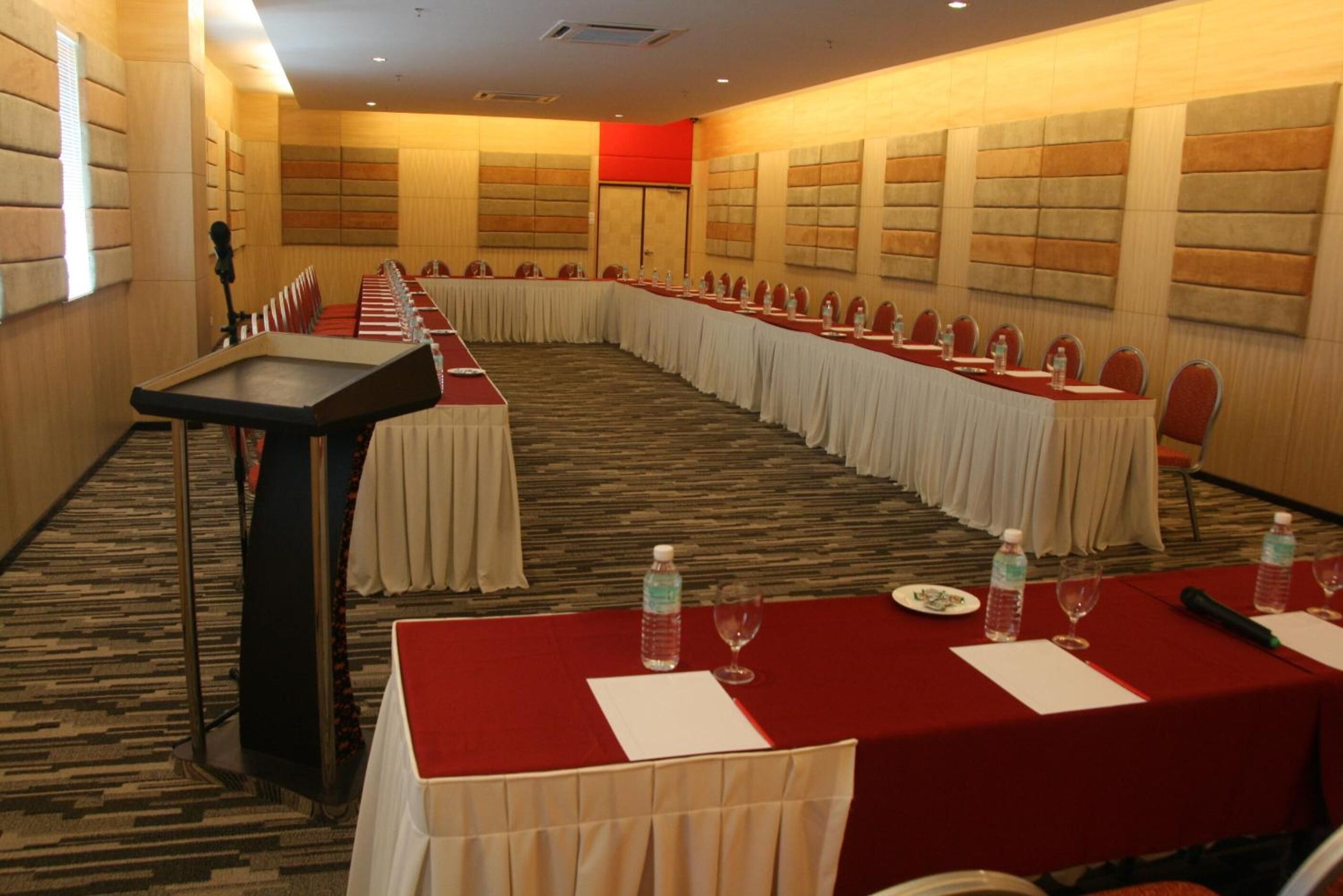 Una sala de conferencias con una larga mesa, sillas y un atril.