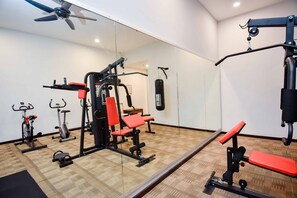 A gym with exercise equipment, a punching bag, and a ceiling fan. - Ritz Garden Hotel Manjung (Seri Manjung)