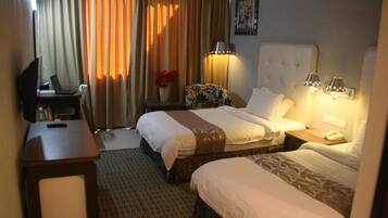 A hotel room with two beds, a desk, a chair, a lamp, and a painting on the wall.