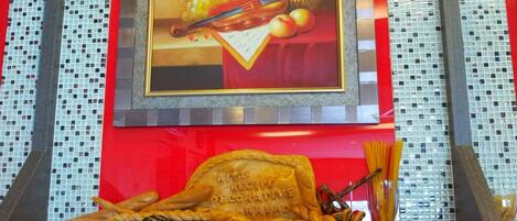 Mostrador de panadería con diferentes panes y pasteles, un cuadro enmarco con frutas y un violín, y un letrero que indica 'River's Reserve Decors & Decouvert Bread'.