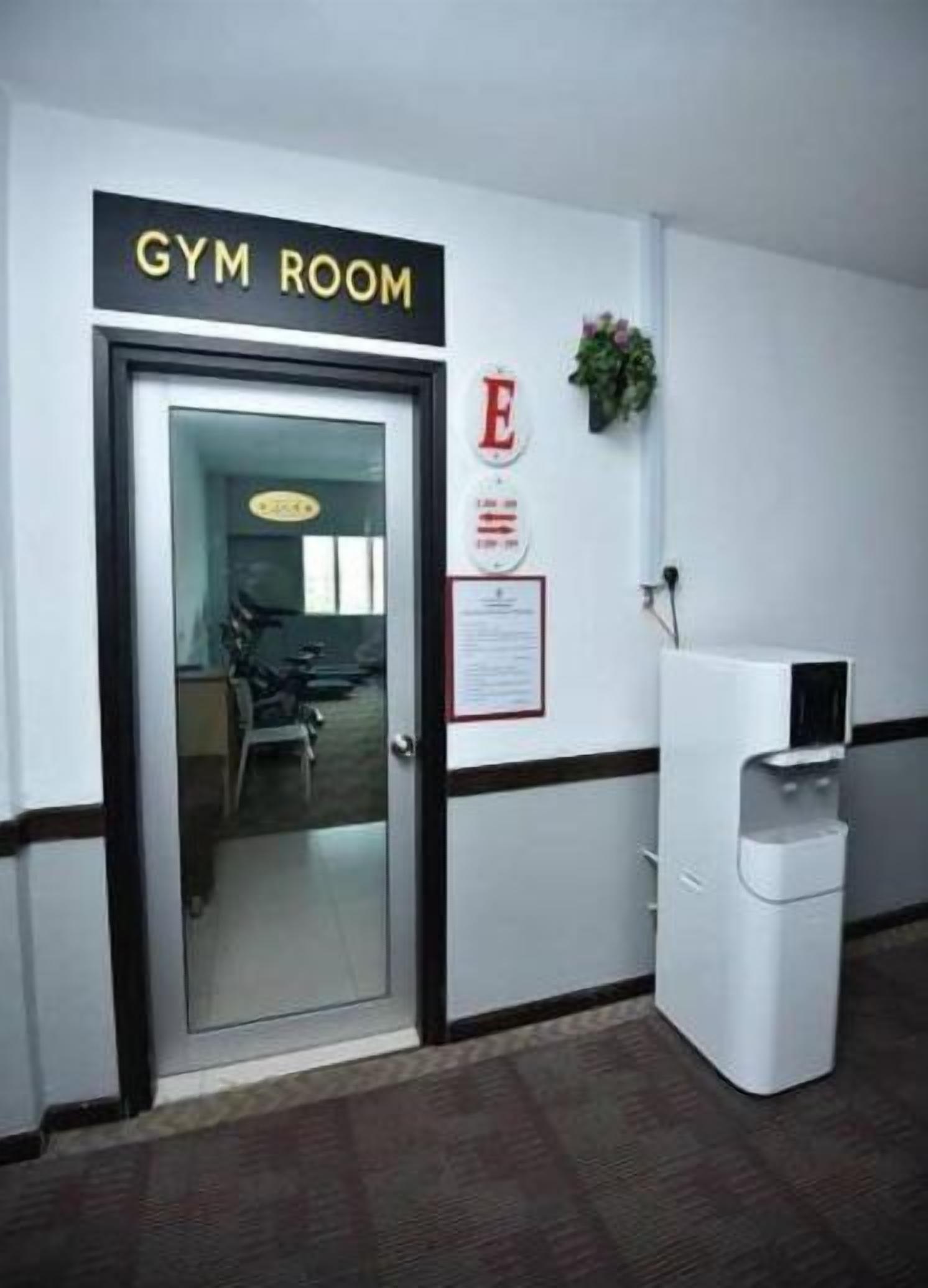 Une salle de sport avec une porte portant l’inscription « SALLE DE SPORT », un distributeur d’eau et une petite plante accrochée au mur.