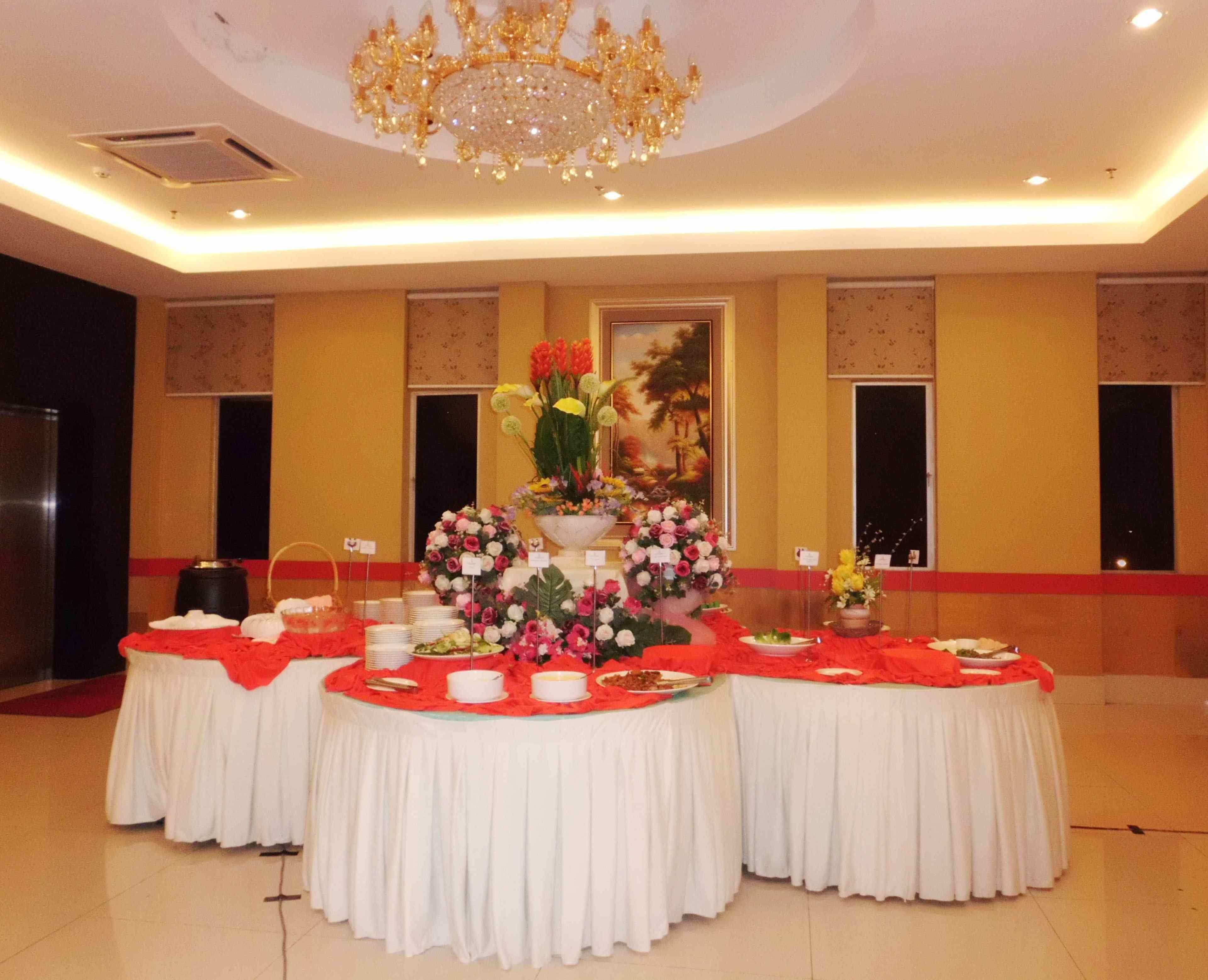A banquet hall with round tables covered in white tablecloths, floral centerpieces, and a chandelier.
