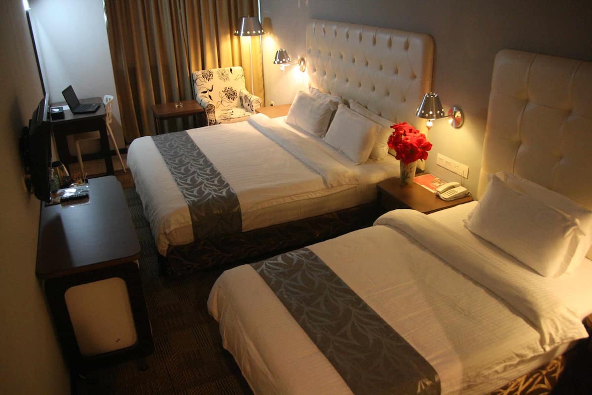 A hotel room with two beds, a desk, a chair, and a small table.