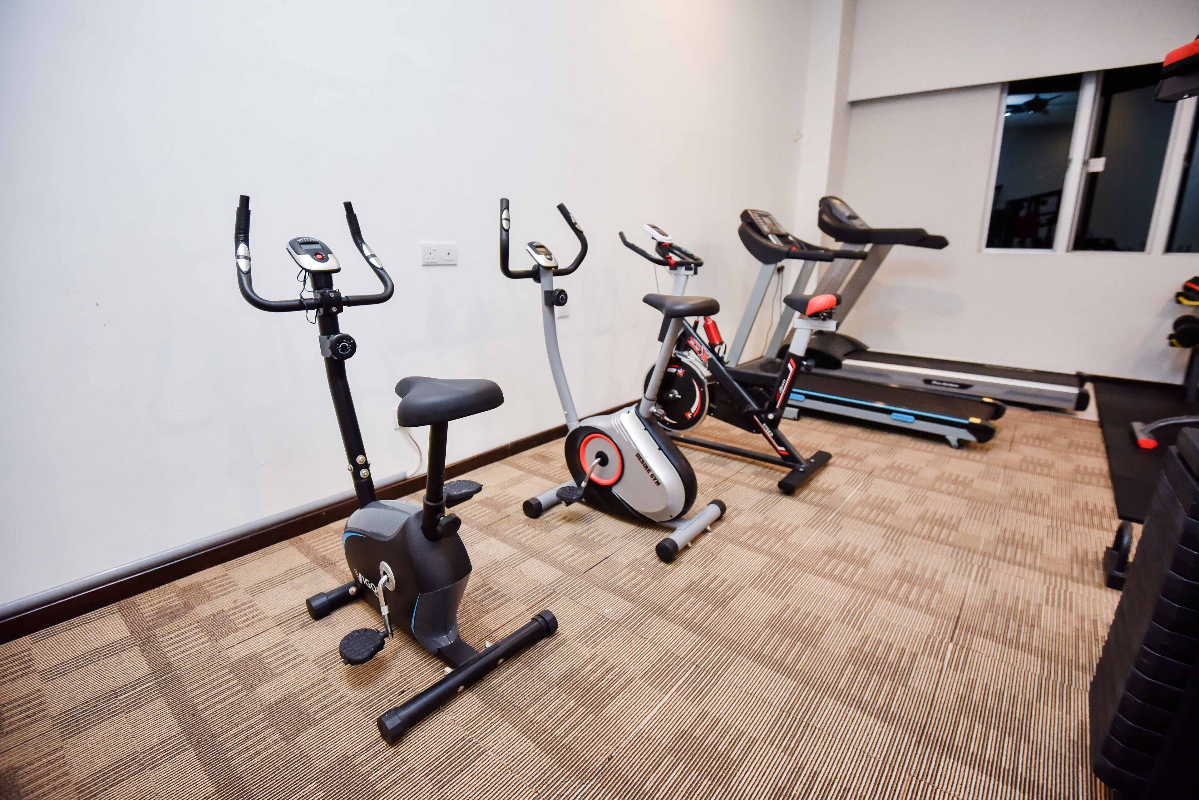 A gym with three stationary bikes and a treadmill.