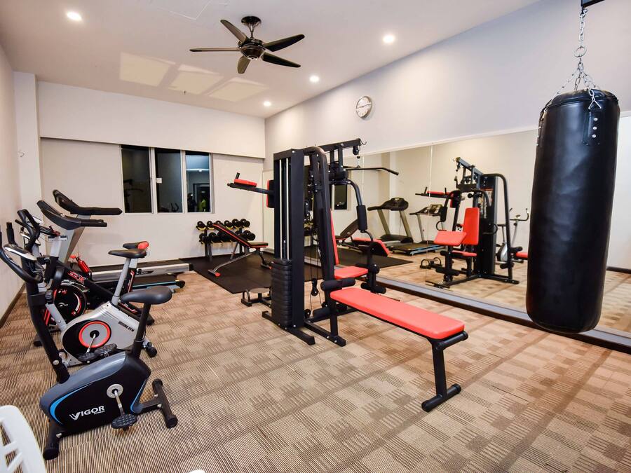 Uma academia com equipamentos de exercícios, um saco de pancadas e um espelho.