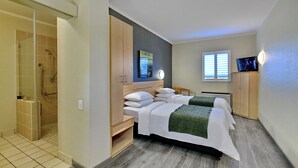 Une chambre d’hôtel avec deux lits, une douche, un téléviseur et une fenêtre avec des stores.