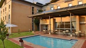 Un hôtel doté d’une piscine, d’un espace extérieur aménagé et de panneaux solaires sur le toit.