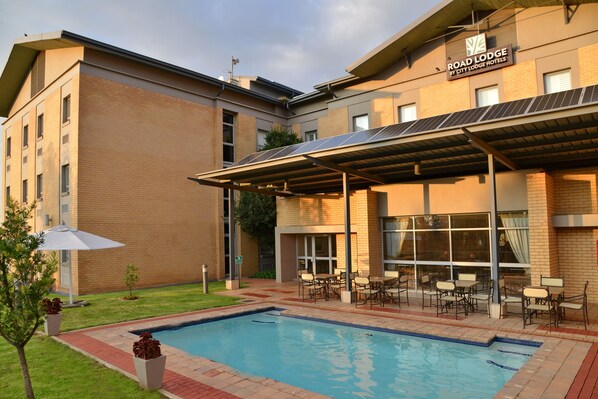 Un hotel con piscina, zona de estar al aire libre y paneles solares en el tejado.